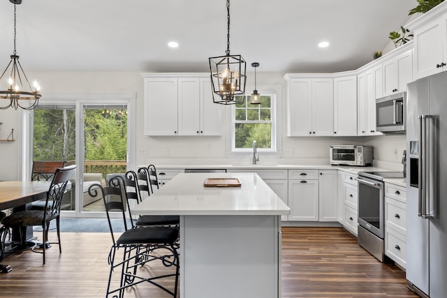 kitchen with stainless steel appliances, dark wood-style floors, a sink, a wealth of natural light, and a notable chandelier