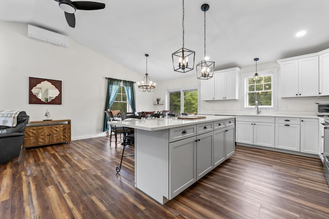 kitchen featuring dark wood finished floors, a wall mounted air conditioner, a breakfast bar, light countertops, and a sink