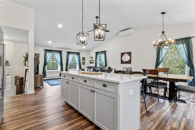 kitchen with a kitchen breakfast bar, an inviting chandelier, a wall mounted air conditioner, light countertops, and dark wood-type flooring