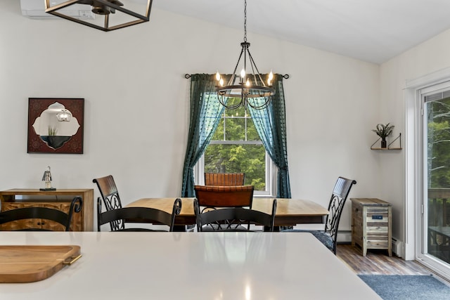 dining area with baseboard heating, a notable chandelier, and wood finished floors