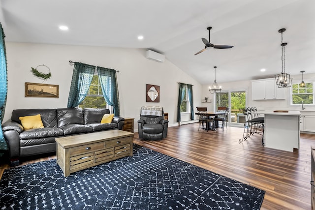 living room with ceiling fan with notable chandelier, a wall unit AC, dark wood finished floors, lofted ceiling, and recessed lighting