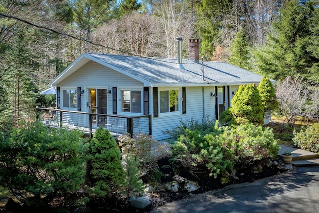 single story home featuring a shingled roof, a chimney, and a deck