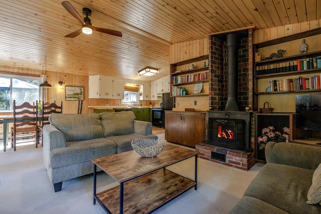 living area featuring a ceiling fan, wood ceiling, and wood walls