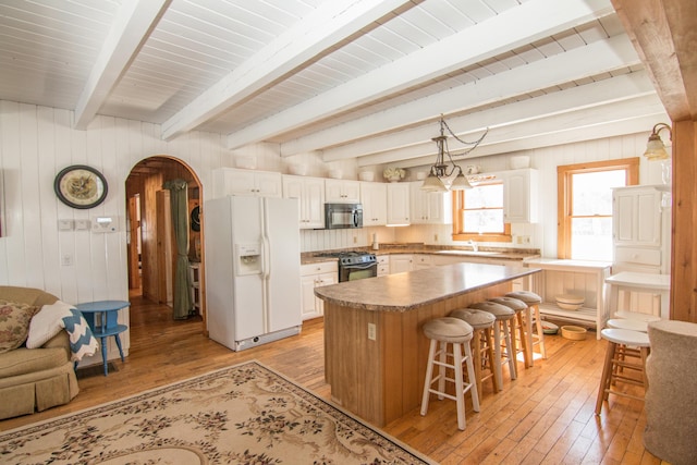 54 Folsom Ridge Rd, Burlington, ME 04417 - kitchen with arched walkways, white fridge with ice dispenser, light wood finished floors, black microwave, and range with gas stovetop