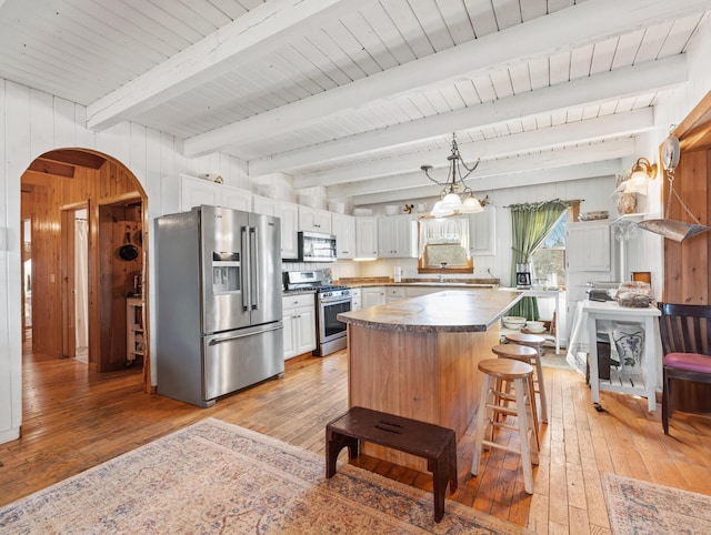 54 Folsom Ridge Rd, Burlington, ME 04417 - kitchen featuring arched walkways, wood walls, stainless steel appliances, and light wood-type flooring