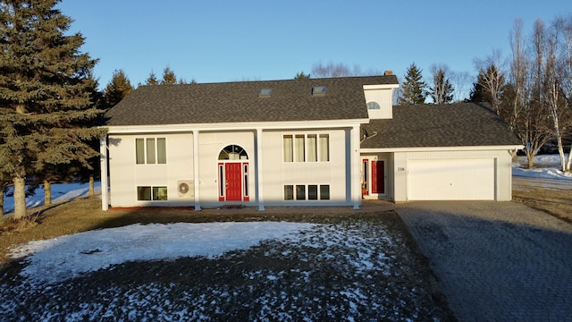 bi-level home with decorative driveway, a shingled roof, and a garage