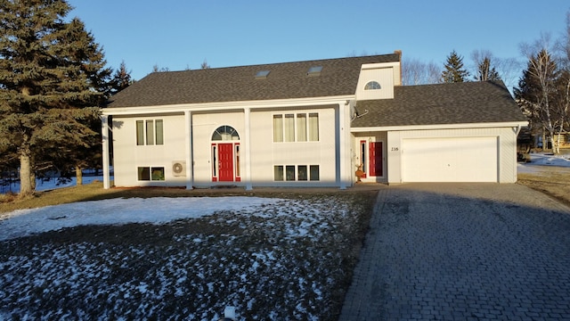 split foyer home featuring a shingled roof, decorative driveway, and a garage