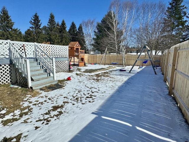 yard layered in snow with a fenced backyard and a playground