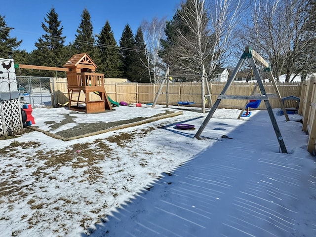snow covered playground featuring a fenced backyard and a playground