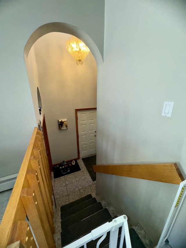 staircase with arched walkways and a chandelier