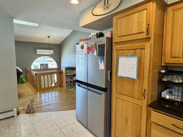 kitchen featuring a baseboard heating unit, a textured ceiling, a wall unit AC, freestanding refrigerator, and light tile patterned floors