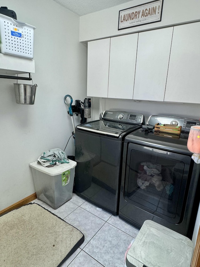 laundry area featuring light tile patterned flooring, independent washer and dryer, a textured ceiling, and cabinet space