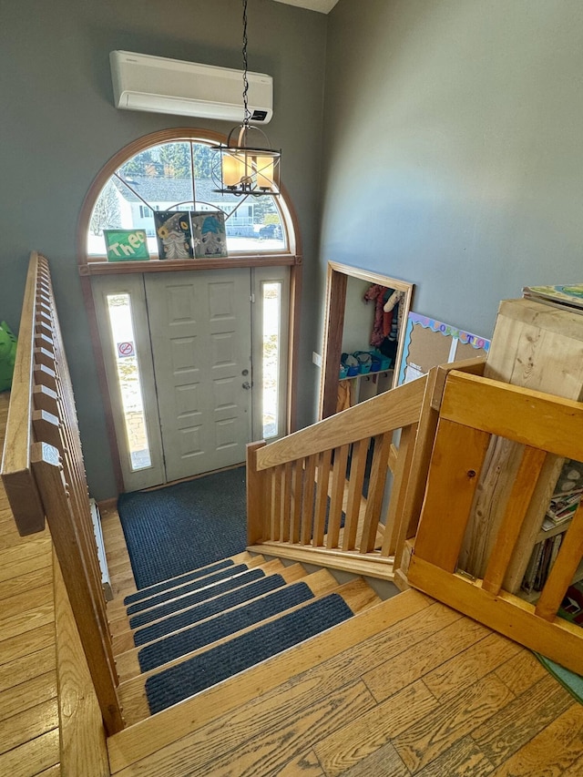 foyer featuring a chandelier, wood finished floors, and a wall unit AC