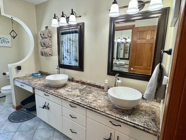 full bathroom with double vanity, tile patterned floors, toilet, and a sink