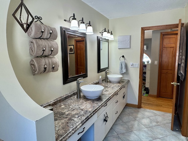 bathroom featuring double vanity, tile patterned floors, baseboards, and a sink