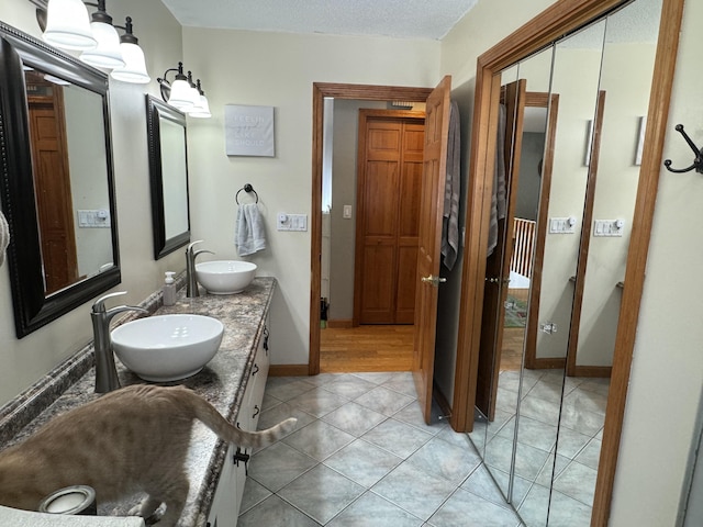 full bath with double vanity, tile patterned floors, baseboards, and a sink