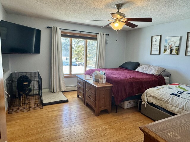 bedroom with a baseboard radiator, light wood-style flooring, a textured ceiling, and ceiling fan