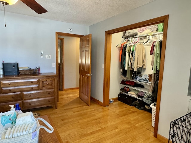 bedroom with a ceiling fan, a closet, baseboards, light wood-style flooring, and a textured ceiling