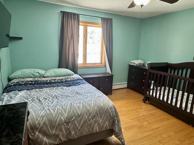 bedroom featuring baseboard heating, wood finished floors, and ceiling fan