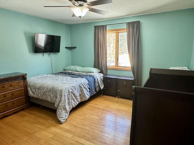 bedroom featuring light wood-style flooring, a textured ceiling, and ceiling fan