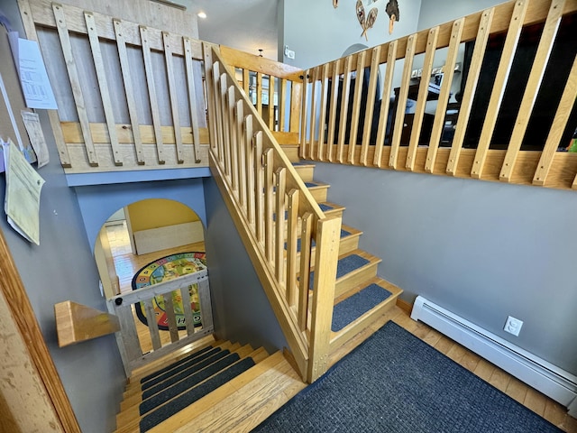 stairway featuring baseboard heating and wood finished floors