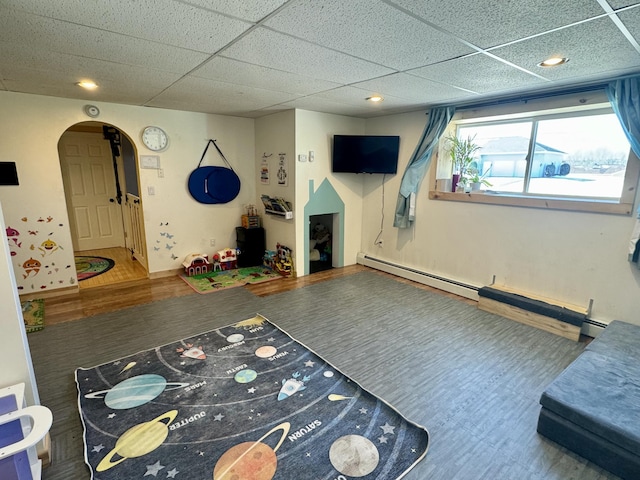 game room featuring recessed lighting, wood finished floors, a baseboard heating unit, arched walkways, and a paneled ceiling