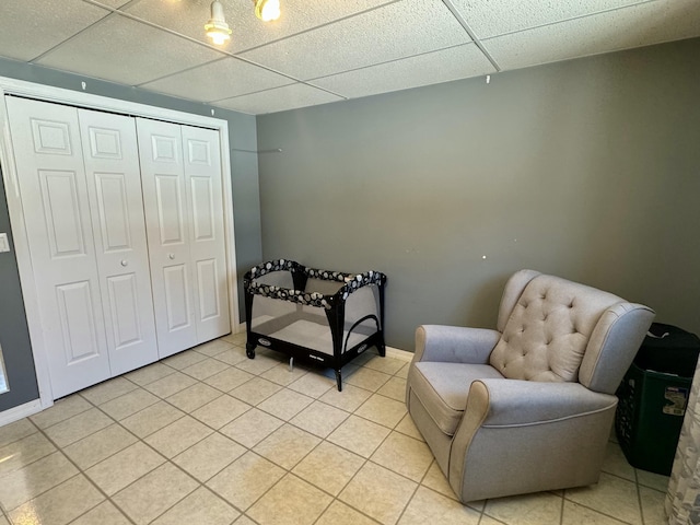 living area with baseboards, a paneled ceiling, and light tile patterned floors