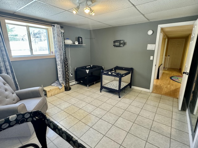 sitting room with baseboards, a paneled ceiling, and light tile patterned floors