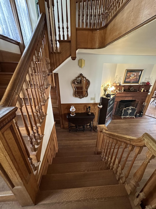 36 Cutler Rd, East Machias, ME 04630 - stairway featuring wood-type flooring, wainscoting, a brick fireplace, and a towering ceiling