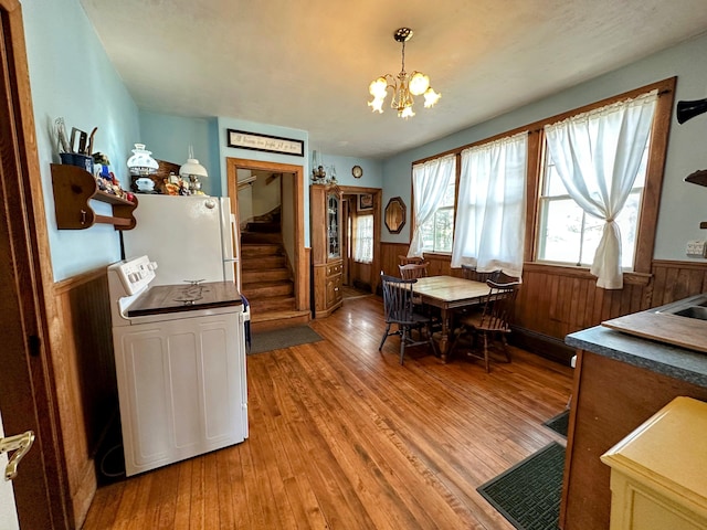 36 Cutler Rd, East Machias, ME 04630 - dining space with stairway, a wainscoted wall, light wood-style floors, a chandelier, and wood walls