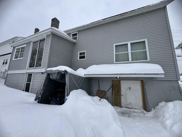 snow covered property with a chimney