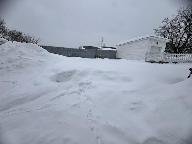 snowy yard with fence, an outbuilding, and a garage