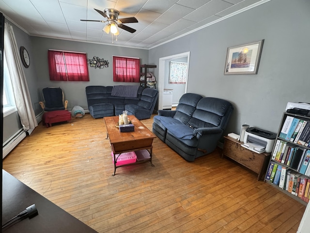 living room featuring baseboard heating, a ceiling fan, ornamental molding, and hardwood / wood-style floors