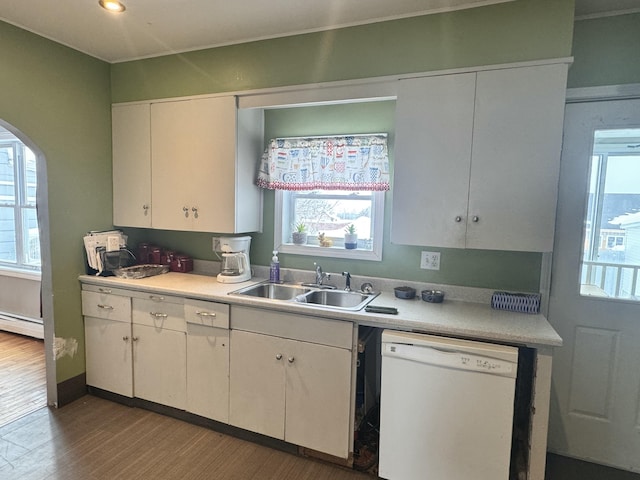 kitchen with a baseboard heating unit, white dishwasher, a sink, and light countertops