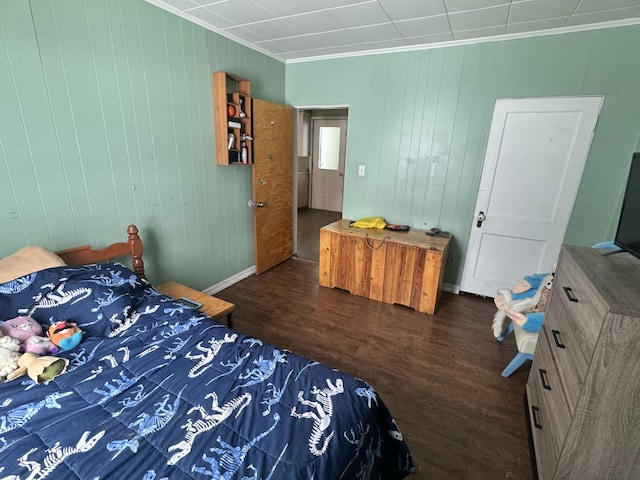 bedroom with wooden walls, crown molding, baseboards, and dark wood-style flooring