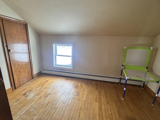 unfurnished bedroom featuring a baseboard radiator, baseboards, and light wood-style flooring