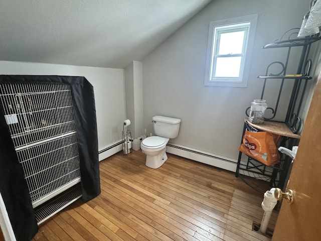 bathroom featuring vaulted ceiling, toilet, baseboard heating, and hardwood / wood-style flooring