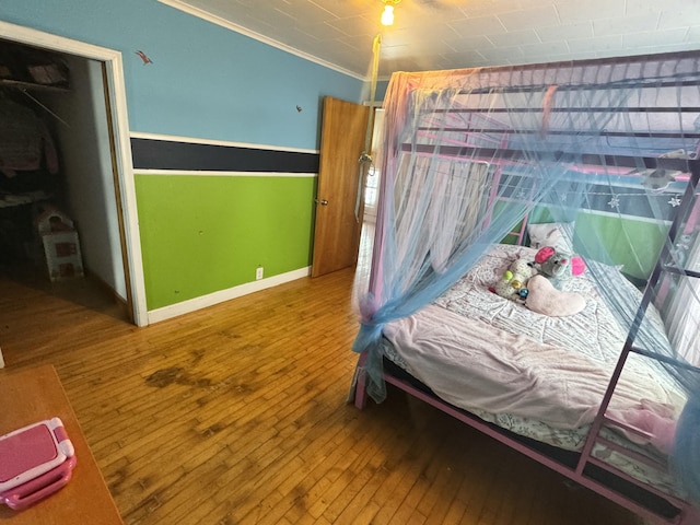 bedroom with hardwood / wood-style flooring, baseboards, and crown molding