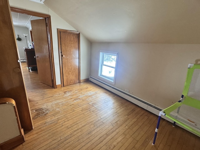 bonus room with a baseboard radiator, vaulted ceiling, and light wood-type flooring