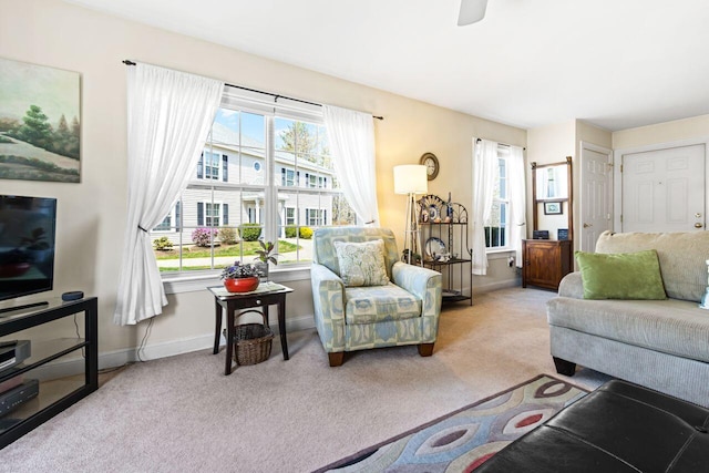 living area with carpet floors, baseboards, and ceiling fan
