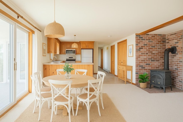 dining area with baseboard heating, light colored carpet, and a wood stove