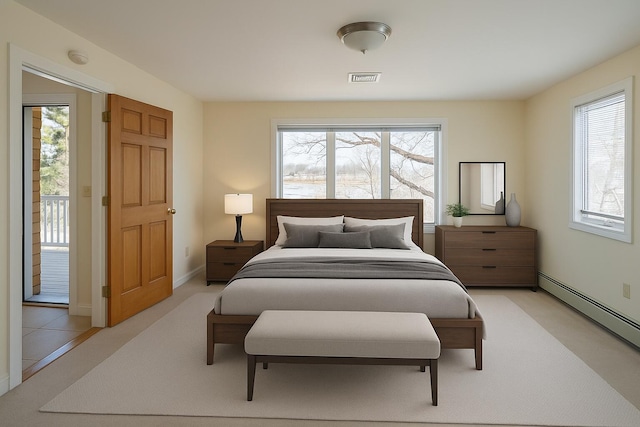 bedroom with a baseboard heating unit, light colored carpet, multiple windows, and visible vents