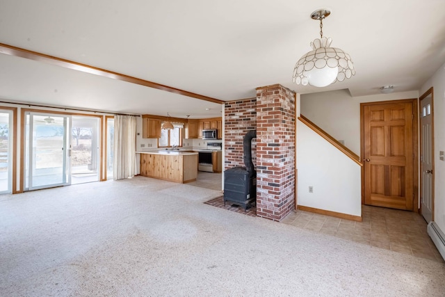 unfurnished living room with light carpet, baseboard heating, baseboards, and a wood stove