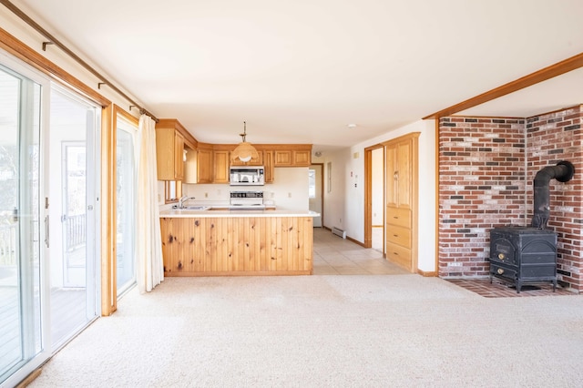 kitchen with a peninsula, a sink, stainless steel microwave, light colored carpet, and range