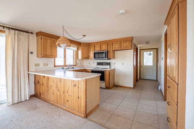 kitchen featuring white range with electric cooktop, a sink, light countertops, stainless steel microwave, and a peninsula