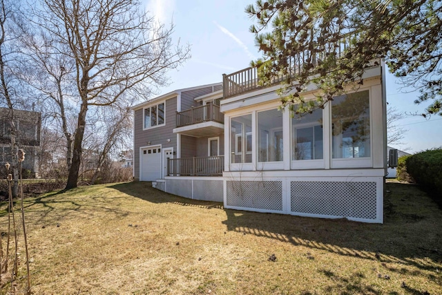 rear view of house featuring an attached garage, a sunroom, a balcony, and a yard