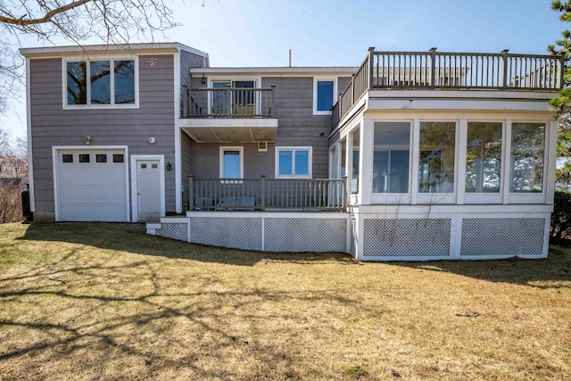 rear view of house with an attached garage, a yard, and a balcony