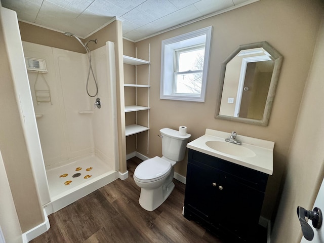 bathroom with wood finished floors, toilet, vanity, crown molding, and a stall shower