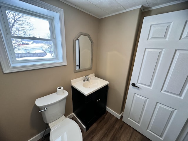bathroom featuring wood finished floors, toilet, vanity, crown molding, and baseboards