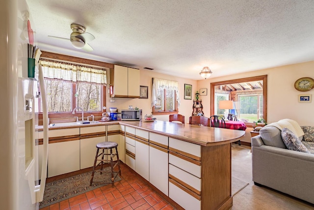 46 Winslow Hill Rd, Nobleboro, ME 04555 - kitchen with a textured ceiling, white refrigerator with ice dispenser, open floor plan, stainless steel microwave, and a peninsula